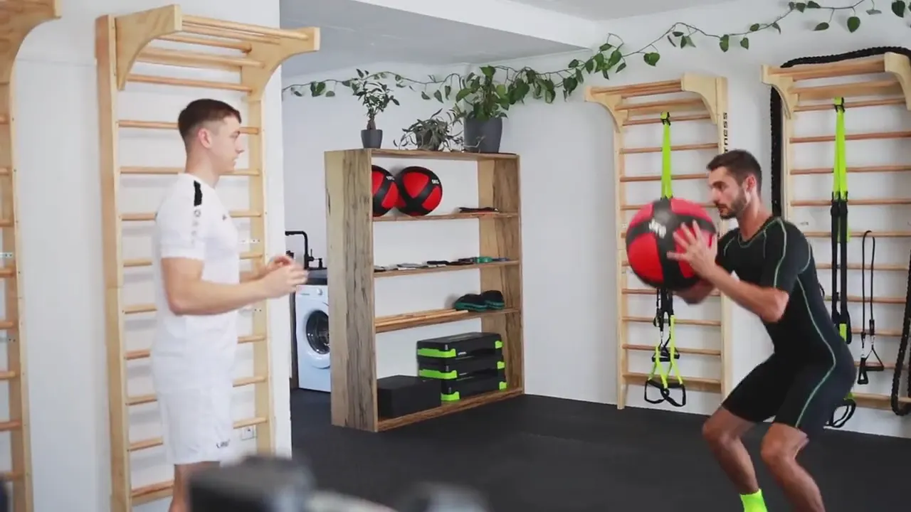 Training mit Medizinball im EMS-Anzug, der Trainer schaut zu