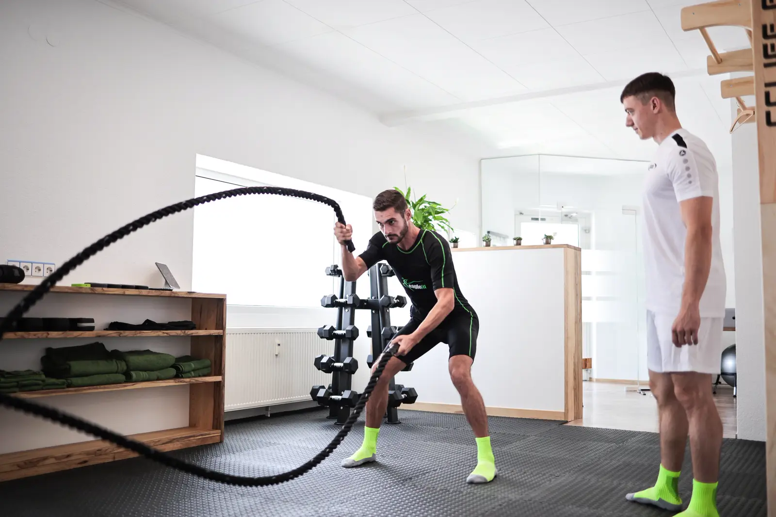 Trainingsraum des EMS Fitnessclub mit Battle Rope, Hantelständer und Empfangstresen